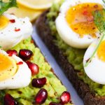 Savor this delicious avocado toast topped with soft-boiled eggs and garnished with pomegranate seeds.